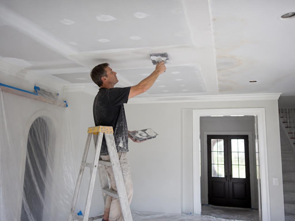Worker repairing a water stained ceiling